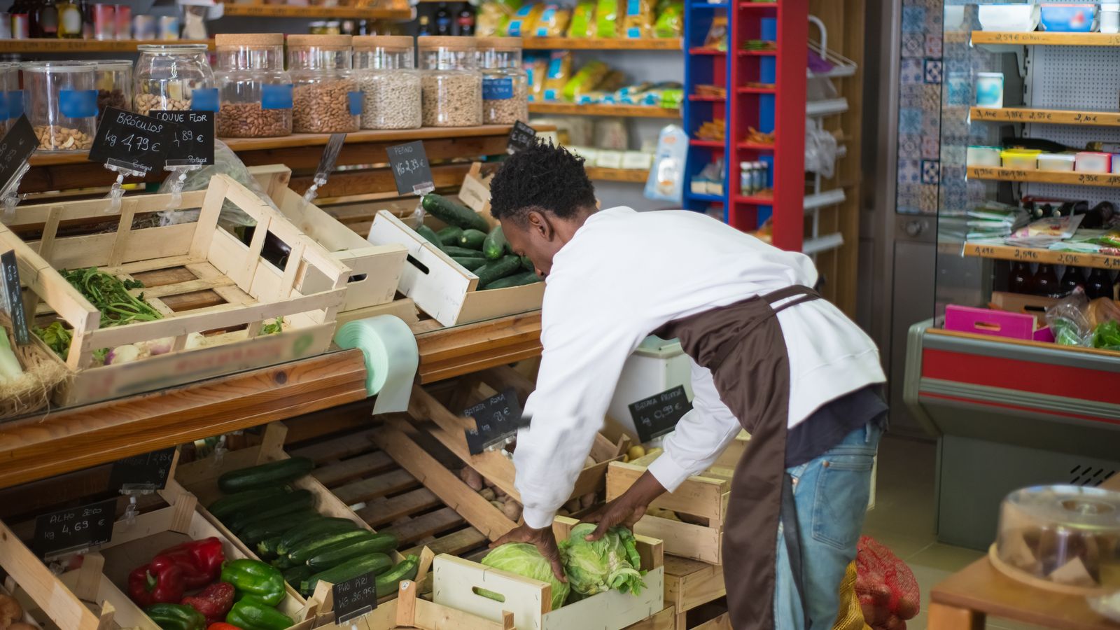 Store worker arranging fresh vegetables in a retail produce display